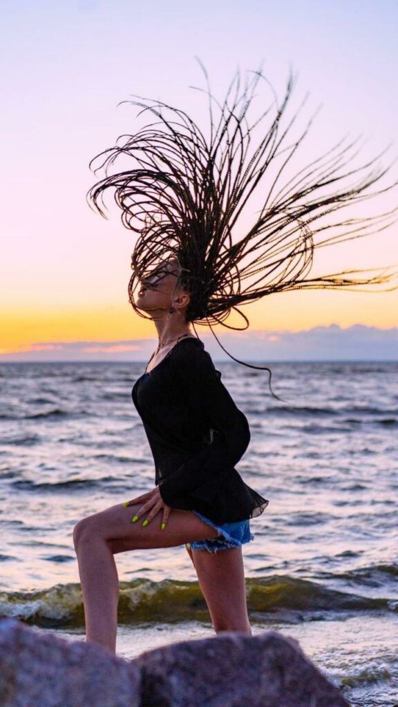 Dívka na břehu moře s afro copánky