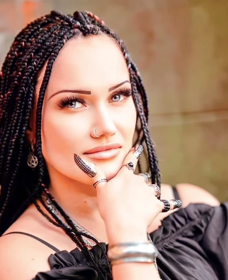 Žena s dlouhými copanky a černým tričkem, zvažující, kde si nechat udělat dredy v Praze.